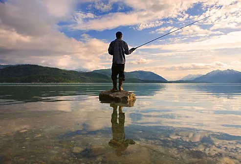 Man fishing in the middle of a scenic lake