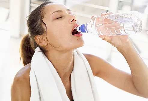 woman drinking water from a bottle after workout