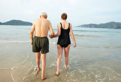 Older Man and Young Woman Walking in the Ocean