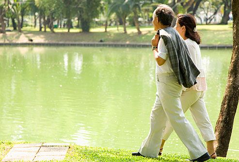 man and woman walking beside pond