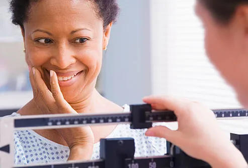 امرأة تبحث سعداء في حين يجري وزنه بواسطة ممرضة