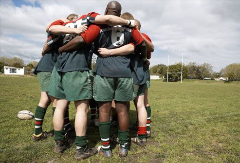 Rugby players standing in circle on sports field