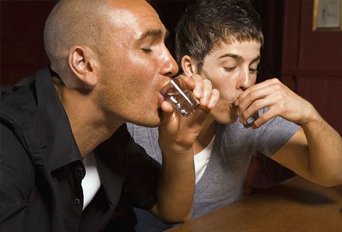 Two young men drinking shots at a bar