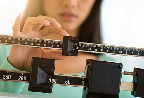woman adjusting weight scale