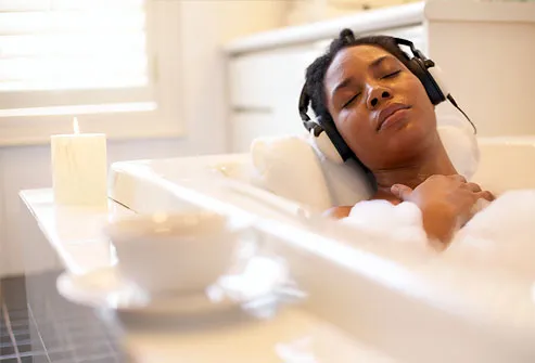 Woman laying in bathtub with headphones
