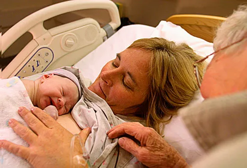 Mother nursing newborn in hospital bed