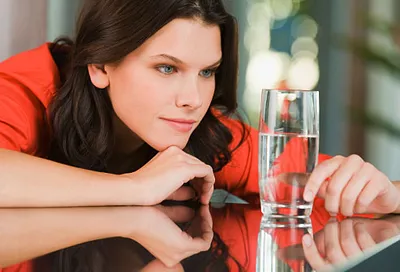Woman contemplating water glass as half full