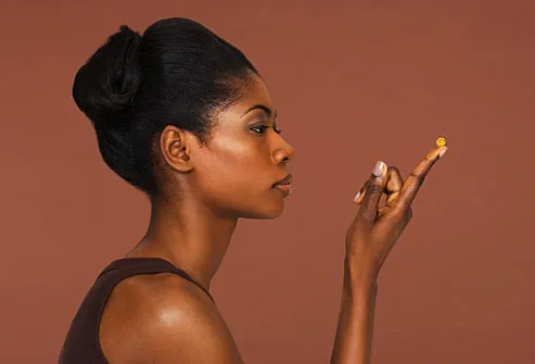 African American woman contemplating a vitamin