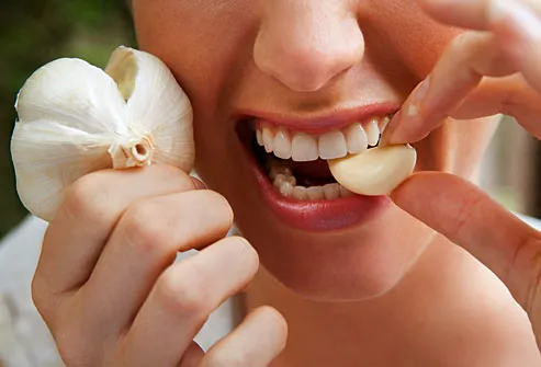 Woman biting into a raw garlic clove