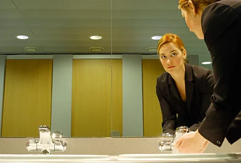 Young businesswoman washing hands in bathroom