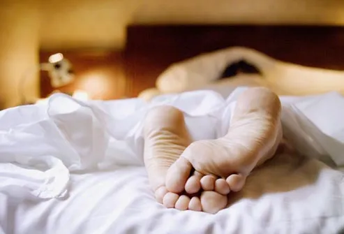 feet of person sleeping in bed