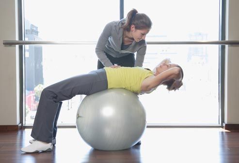 woman on exercise ball with trainer