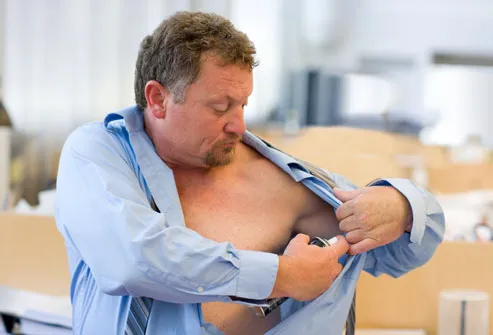 man applying deodorant in office