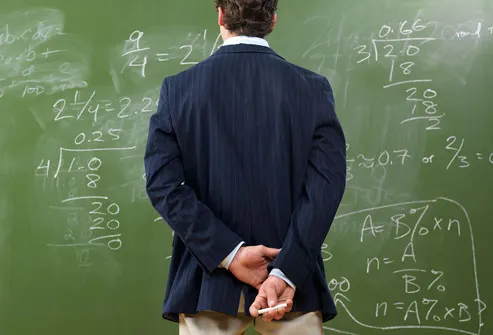 Man Looking at Math Problems on Blackboard