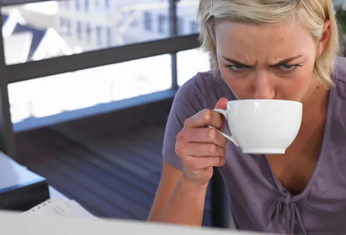 Tired looking woman drinking coffee