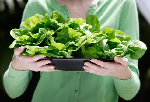woman holding plate of leafy greens