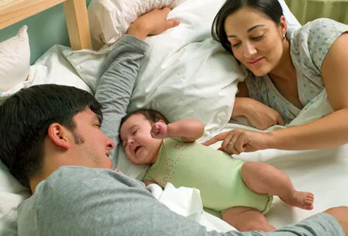 Couple in bed with newborn between them