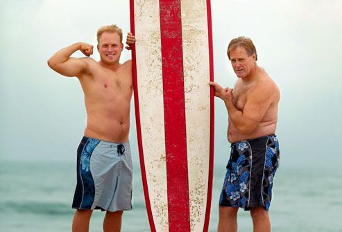 Senior man and young man on beach with surfboard