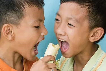 two boys sharing a banana