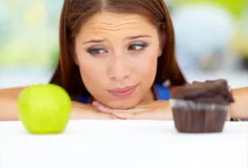 woman looking at apple ans cupcake