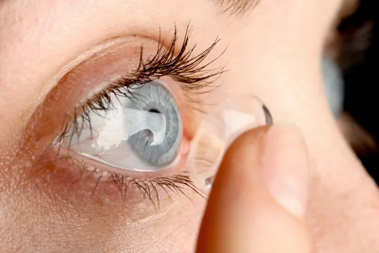 Woman putting in contact lens, ECU of eye
