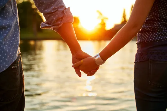 photo of couple holding hands next to river