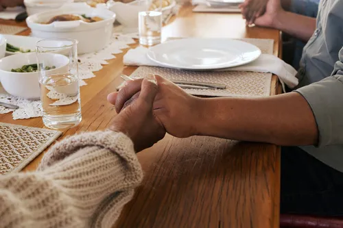 photo of family sitting at table holding hands