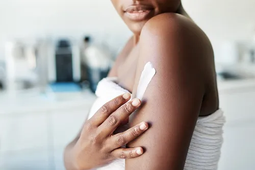 photo of woman applying moisturizer
