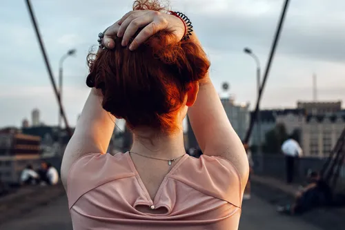 photo of redhead woman holding hair on bridge