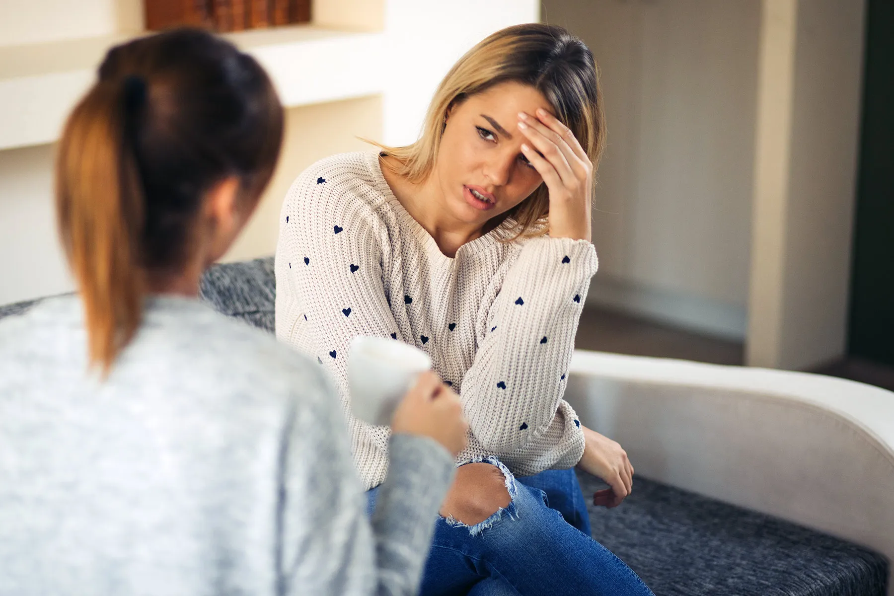 photo of young woman comforting her friend