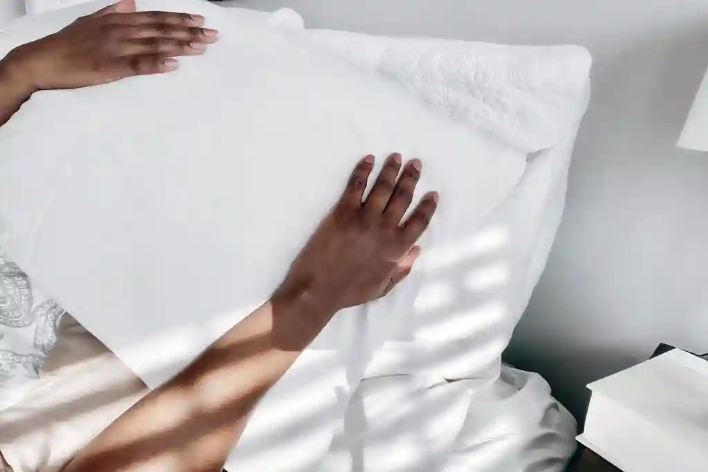 photo of woman in bed with pillow covering head