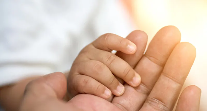 man holding baby's hand