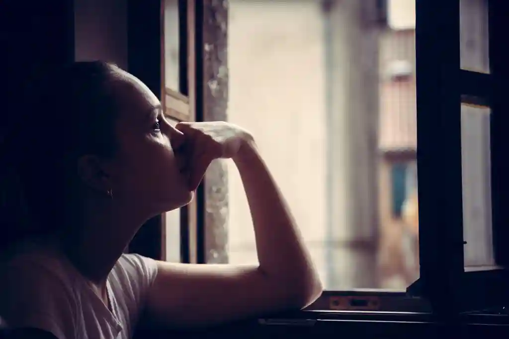 woman looking out the window with sadness