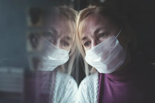 woman in face mask at window