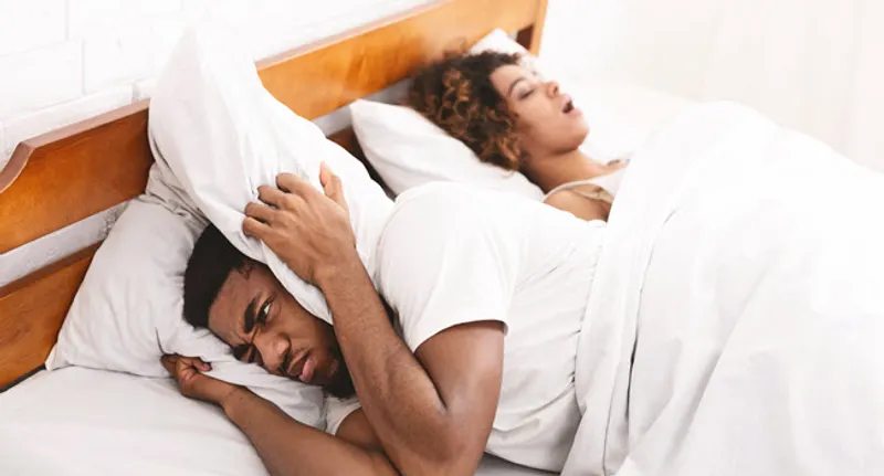 irritated man sleeping next to woman snoring
