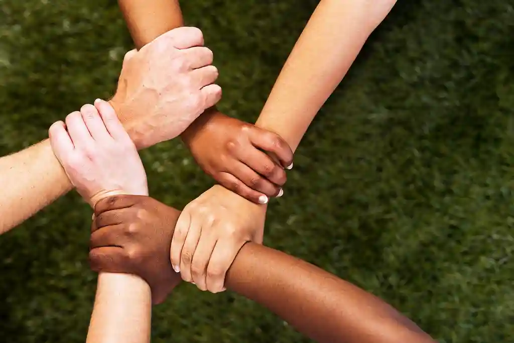 photo of five mixed hands clasped in unity