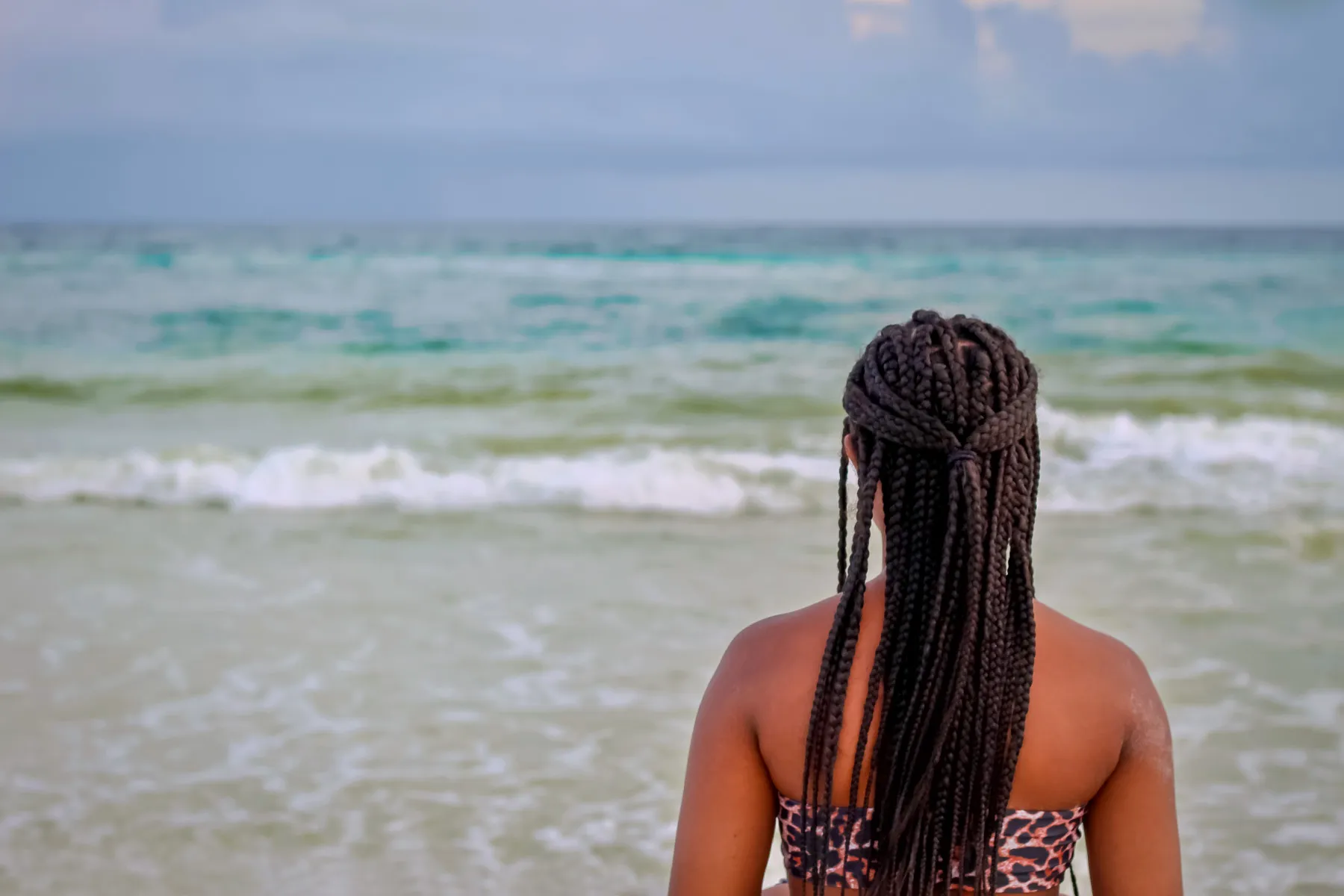 photo of woman with braided hair looking at sea 
