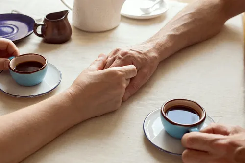 senior couple holding hands and drinking coffee 