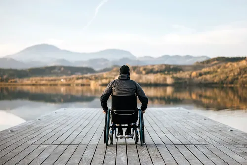 photo of man in wheelchair admiring lake