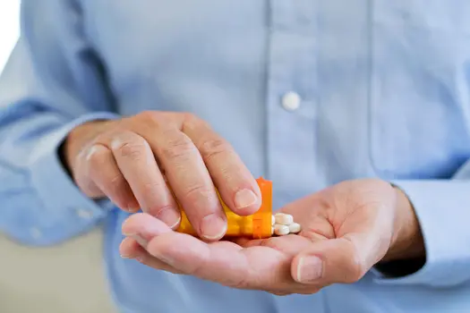 photo of man pouring prescription pills into hand
