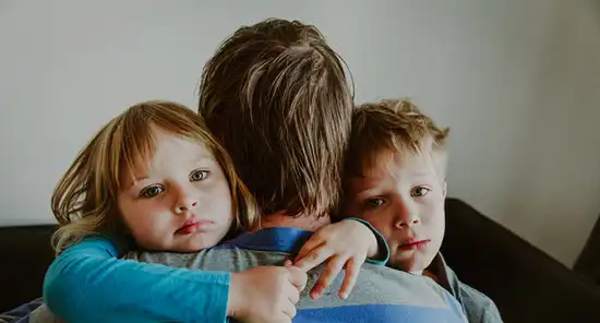 father hugging sad children