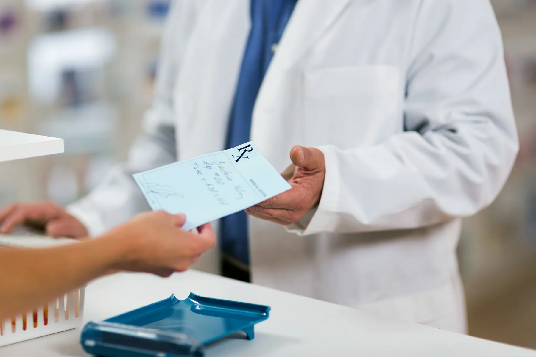 photo of woman handing prescription to pharmacist