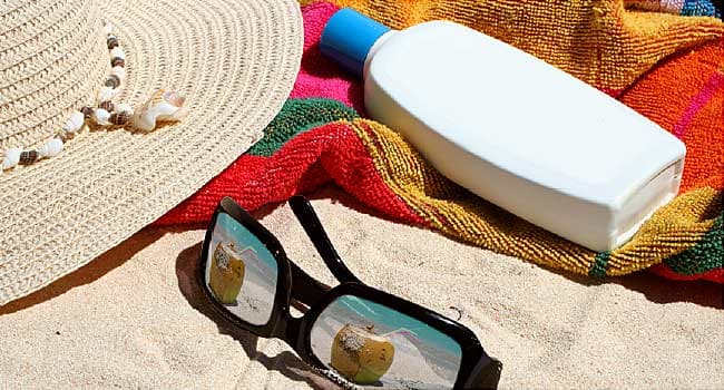 sunglasses and sunscreen bottle on beach