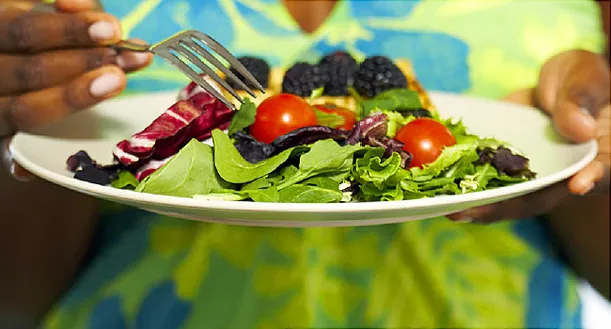 Woman holding plate of mixed salad