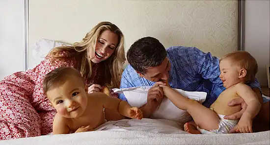 Caucasian family playing on bed