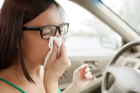 photo of woman blowing nose in car