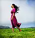 Woman standing in grass field barefoot, wind blowi