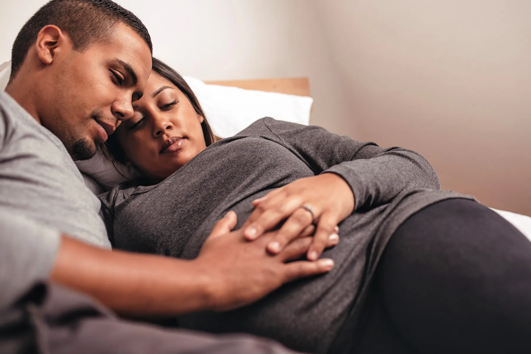 photo of young african pregnant couple in bed