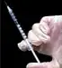gloved hand holding syringe
