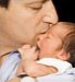 father kissing newborn baby